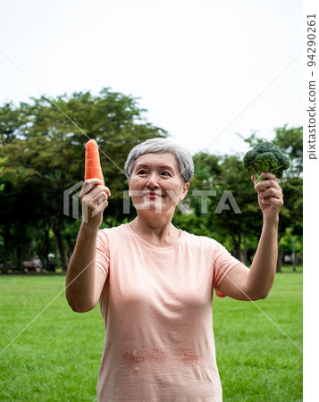 Happy senior asian woman smiling and standing with organic fruits and vegetables in hands enjoying nature fresh air in park, suitable for elderly healthy eating or vegetarian food Happy senior asian woman smiling and standing with organic fruits and vegetables in hands enjoying nature fresh air in park, suitable for elderly healthy eating or vegetarian food 94290261