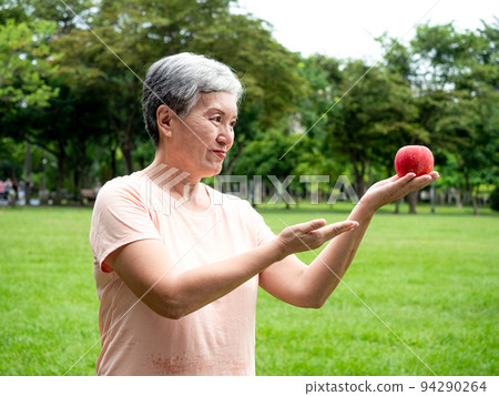 享受亞洲女性微笑站的歡樂娛樂，手工製作的水果，在公園裡享受大自然的清新空氣，適合老年人的健康飲食理念。 94290264