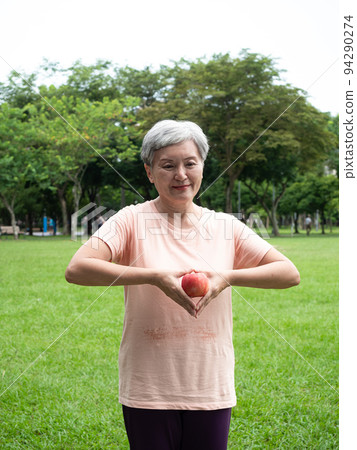 享受亞洲女性微笑站的歡樂娛樂,手工製作的水果,在公園裡享受大自然的清新空氣,適合老年人的健康飲食理念。 享受亞洲女性微笑站的歡樂娛樂,手工製作的水果,在公園裡享受大自然的清新空氣,適合老年人的健康飲食理念。 94290274