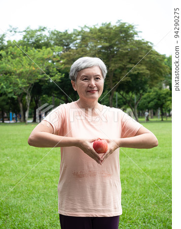 享受亞洲女性微笑站的歡樂娛樂，手工製作的水果，在公園裡享受大自然的清新空氣，適合老年人的健康飲食理念。 94290275