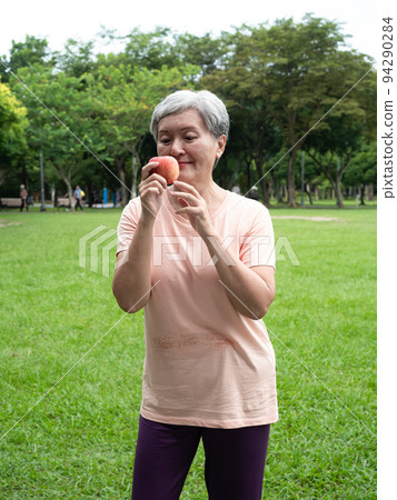 享受亞洲女性微笑站的歡樂娛樂，手工製作的水果，在公園裡享受大自然的清新空氣，適合老年人的健康飲食理念。 94290284