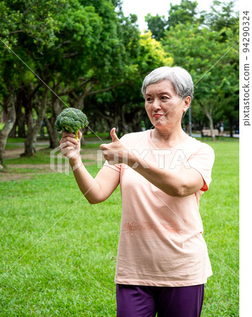 Happy senior asian woman smiling and standing with organic fruits and vegetables in hands enjoying nature fresh air in park, suitable for elderly healthy eating or vegetarian food Happy senior asian woman smiling and standing with organic fruits and vegetables in hands enjoying nature fresh air in park, suitable for elderly healthy eating or vegetarian food 94290324
