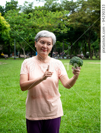 Happy senior asian woman smiling and standing with organic fruits and vegetables in hands enjoying nature fresh air in park, suitable for elderly healthy eating or vegetarian food Happy senior asian woman smiling and standing with organic fruits and vegetables in hands enjoying nature fresh air in park, suitable for elderly healthy eating or vegetarian food 94290333