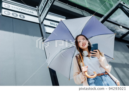 Beautiful Asian woman happiness holding umbrella and listening favourite music on headphones from mobile phone, Happiness relaxation summer in park with music Beautiful Asian woman happiness holding umbrella and listening favourite music on headphones from mobile phone, Happiness relaxation summer in park with music 94293021