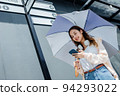 Beautiful Asian woman happiness holding umbrella and listening favourite music on headphones from mobile phone, Happiness relaxation summer in park with music 94293022