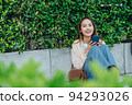 Beautiful Asian woman listening favourite music on headphones from mobile phone, Happiness relaxation summer in park with music riding bicycle in green park. 94293026