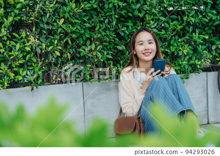 Beautiful Asian woman listening favourite music on headphones from mobile phone, Happiness relaxation summer in park with music riding bicycle in green park. Beautiful Asian woman listening favourite music on headphones from mobile phone, Happiness relaxation summer in park with music riding bicycle in green park. 94293026