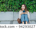 Beautiful Asian woman listening favourite music on headphones from mobile phone, Happiness relaxation summer in park with music riding bicycle in green park. 94293027
