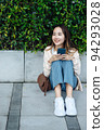 Beautiful Asian woman listening favourite music on headphones from mobile phone, Happiness relaxation summer in park with music riding bicycle in green park. 94293028