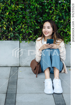 Beautiful Asian woman listening favourite music on headphones from mobile phone, Happiness relaxation summer in park with music riding bicycle in green park. 94293028
