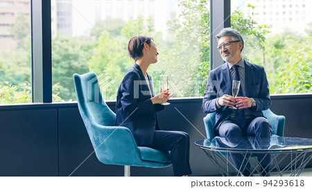 Executive man and woman chatting while drinking champagne in the lobby 94293618