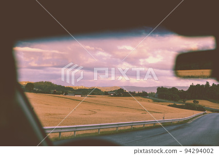 View from the windscreen. Driving a car on a mountain road during sunset. Nature of Norway 94294002