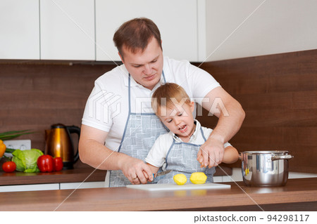 Concept food and nutrition. Shot of two cheerful dad and son posing in kitchen Concept food and nutrition. Shot of two cheerful dad and son posing in kitchen 94298117
