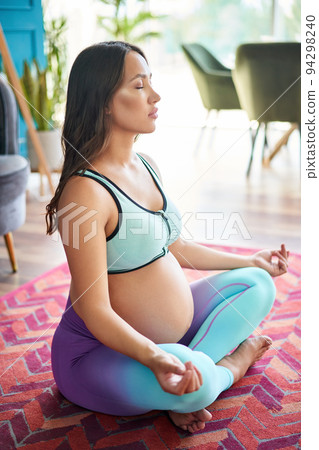 Sporty pregnant woman in sportswear practicing yoga, meditating in Lotus pose 94298240