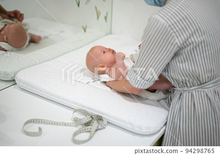 Baby lying on his back being messured during a standard medical checkup. Baby lying on his back being messured during a standard medical checkup. 94298765