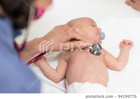 Baby lying on his back as his doctor examines him during a standard medical checkup 94298776