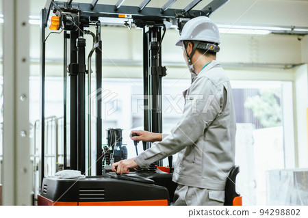 Qualified male employee driving forklift in distribution warehouse 94298802