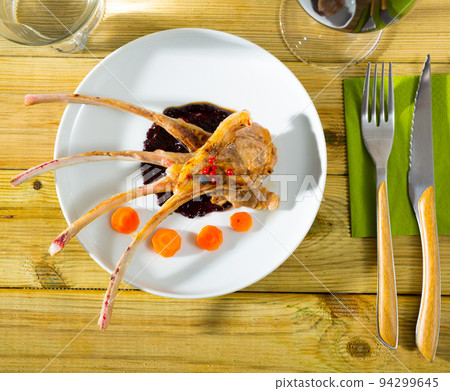 Baked under tasty lamb ribs served with sauce and carrots Baked under tasty lamb ribs served with sauce and carrots 94299645