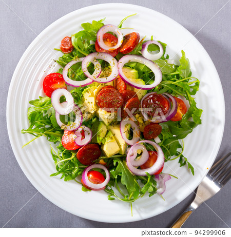 Top view of arugula salad with avocado, roasted chorizo sausage 94299906