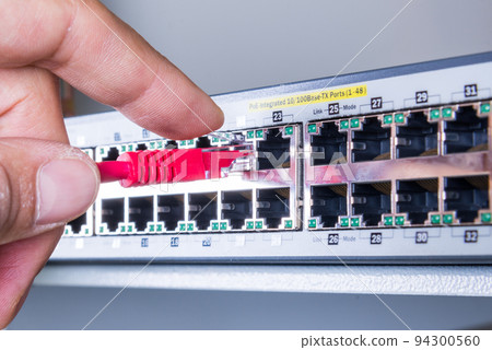 hand of administrator plugging in red patch cable into empty switchboard hand of administrator plugging in red patch cable into empty switchboard 94300560