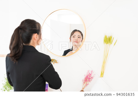 一個女人在鏡子前檢查自己的外表 94301635