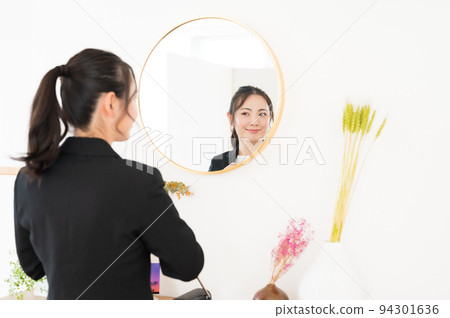 一個女人在鏡子前檢查自己的外表 一個女人在鏡子前檢查自己的外表 94301636