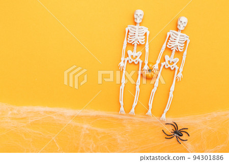 skeletons with pumpkin, spider web and black spiders on orange background. halloween concept skeletons with pumpkin, spider web and black spiders on orange background. halloween concept 94301886
