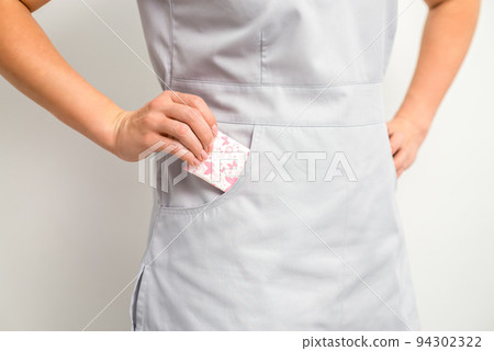 The female hand puts menstrual sanitary pads into her pocket, close up 94302322