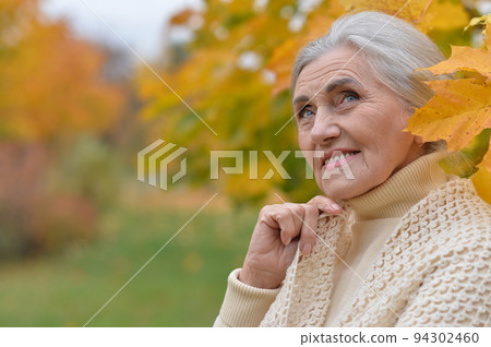 Senior woman walking in the park in autumn Senior woman walking in the park in autumn 94302460