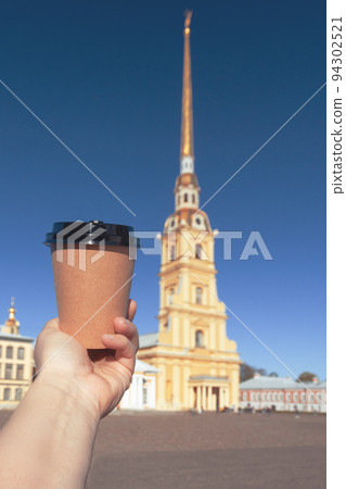 paper cup of natural coffee in women's hand in center of St. Petersburg, Russia paper cup of natural coffee in women's hand in center of St. Petersburg, Russia 94302521