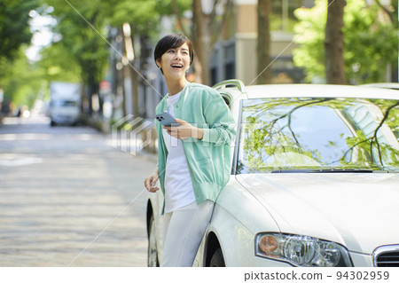 一位年輕女子在車旁看智能手機 94302959