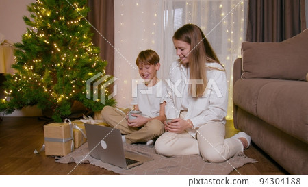 Brother and sister watch Christmas movies on a laptop 94304188