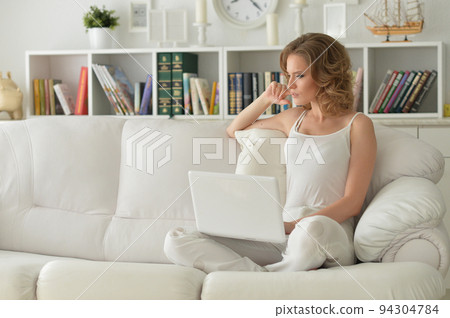Portrait of a beautiful woman with a laptop on the sofa 94304784