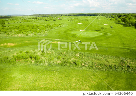 View from a distance of the golf course from a height. Green field and sand bunkers for playing golf.  94306440
