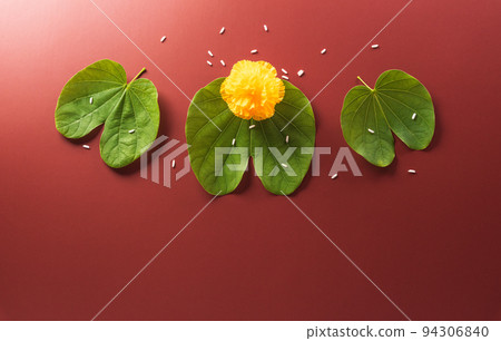 Happy Dussehra. Yellow flowers, green leaf and rice on dark paper background. Dussehra Indian Festival concept. Happy Dussehra. Yellow flowers, green leaf and rice on dark paper background. Dussehra Indian Festival concept. 94306840
