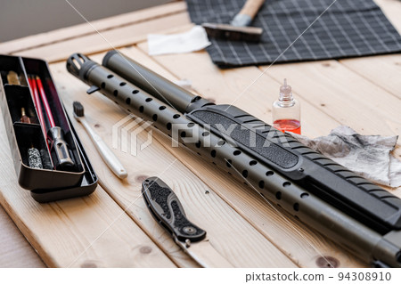 Disassembled rifle with cleaning tools on table of weapons workshop 94308910