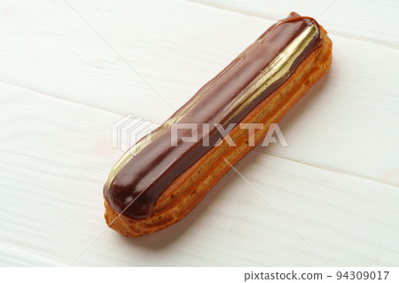 Chocolate eclair on white wooden background, close up 94309017