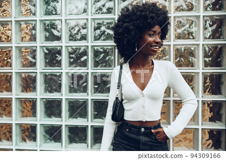 African young woman looking happy while posing against glass wall African young woman looking happy while posing against glass wall 94309166