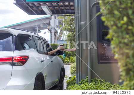 Hand Man in car receiving coffee in drive thru fast food restaurant.  94310875