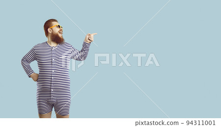 Funny fat guy in striped pajamas or swimsuit laughing and showing something on copy space 94311001