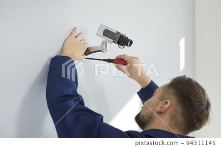 Technician worker install security camera on wall Technician worker install security camera on wall 94311145