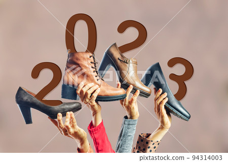 Hands holding different womens shoes and boots with year 2023 on them. New year concept Hands holding different womens shoes and boots with year 2023 on them. New year concept 94314003