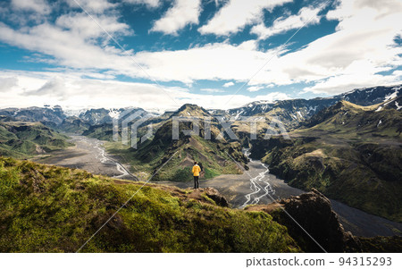 Scenery of Valahnukur viewpoint with female hiker standing on peak and krossa river through in icelandic highlands at Thorsmork, Iceland 94315293