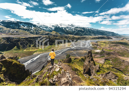 Scenery of Valahnukur viewpoint with female hiker standing on peak and krossa river through in icelandic highlands at Thorsmork, Iceland 94315294