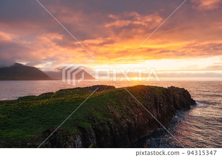 Sunset over mountain cape with puffins colony in summer on Eastern at Borgarfjardarhofn, Iceland Sunset over mountain cape with puffins colony in summer on Eastern at Borgarfjardarhofn, Iceland 94315347