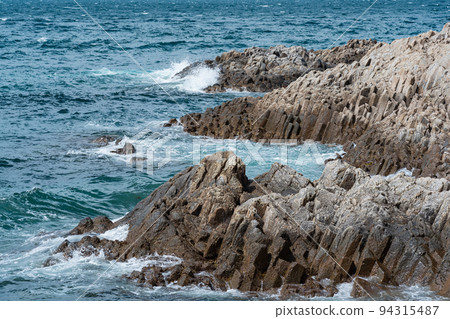 rocky seashore formed by columnar basalt against the sea, coastal landscape of the Kuril Islands rocky seashore formed by columnar basalt against the sea, coastal landscape of the Kuril Islands 94315487