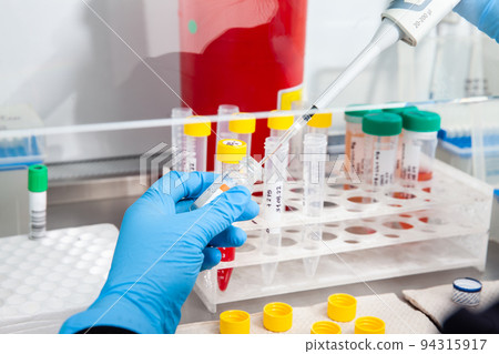 Scientist preparing blood samples for karyotipe and fluorescence in situ hybridization in the  laminar air flow cabinet. Blood sample preparation for diagnosis. Blood test. 94315917