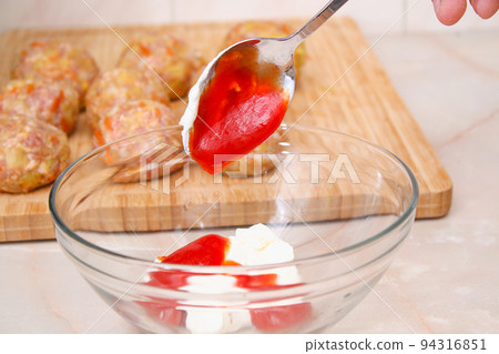 A man puts tomato paste, ketchup for pouring to 94316851
