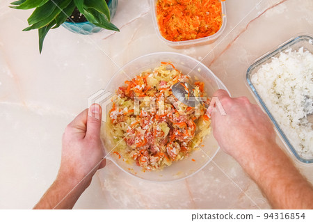 A man mixes minced meat, cabbage, onions, carrots 94316854