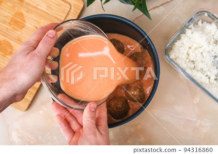 A man puts lazy cabbage rolls into multicooker A man puts lazy cabbage rolls into multicooker 94316860